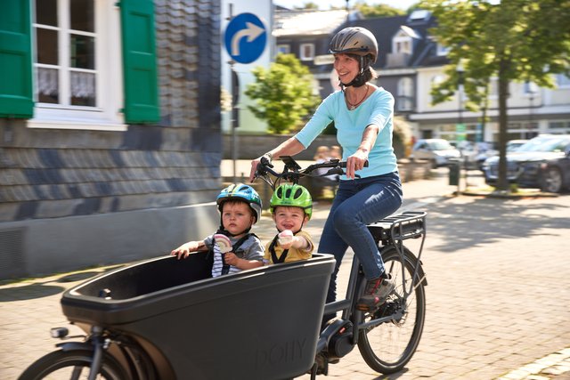 Frau fährt 2 Kleinkinder mit Lastenrad