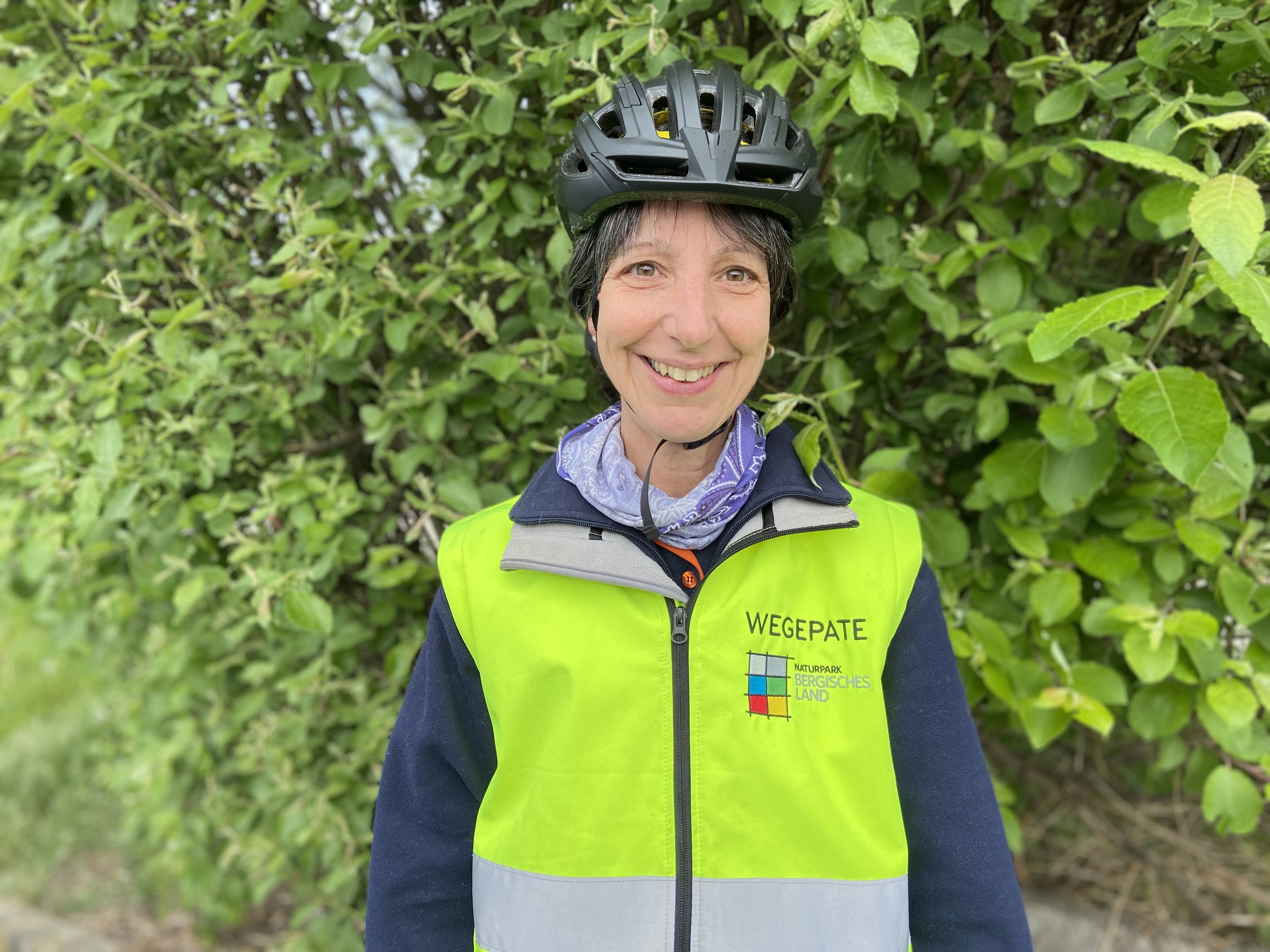 Sabine Krämer-Kox in ihrer Rolle als Radwegpatin mit Wegpatinnen-Weste und Fahrradhelm.